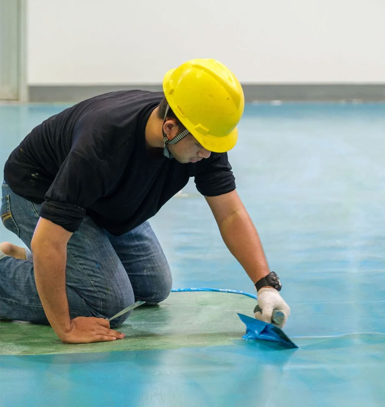 Operario aplicando resina al suelo.